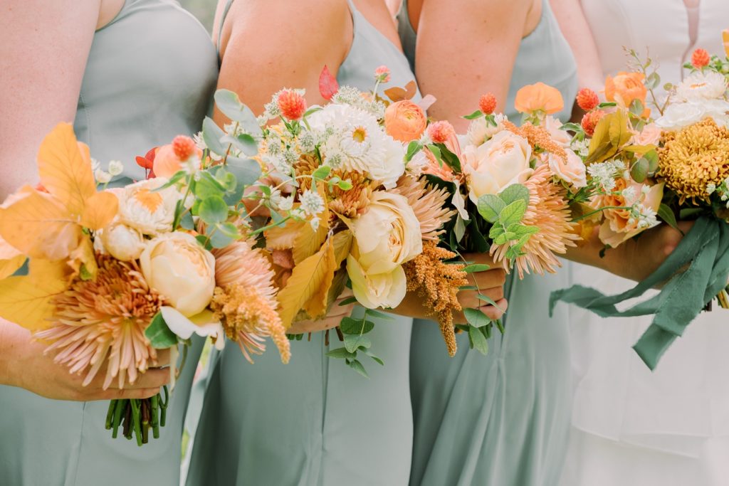 Sage bridesmaids with orange, marigold and yellow bouquet