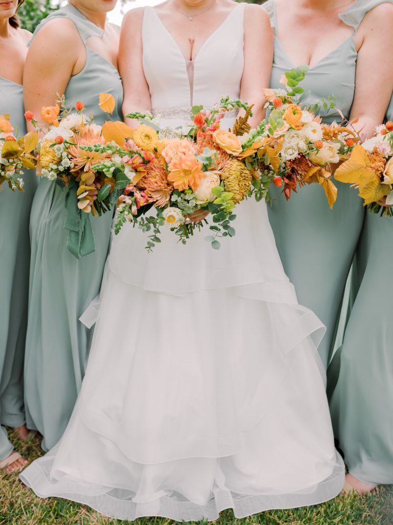 Sage bridesmaids with orange, marigold and yellow bouquet