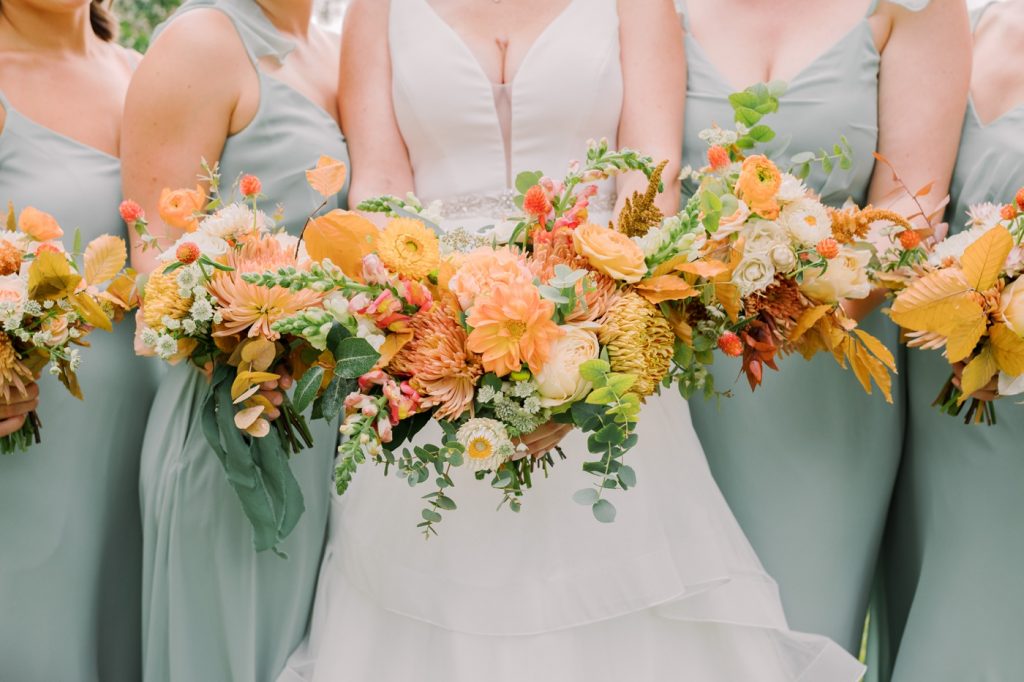 Sage bridesmaids with orange, marigold and yellow bouquet