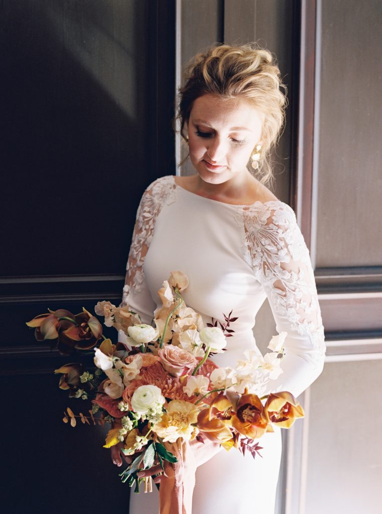 Bridal bouquet by Gray Harper with copper cymbidium orchids, cream ranunculus, mauve roses, and handpicked flowers in shades of honey and blush. 