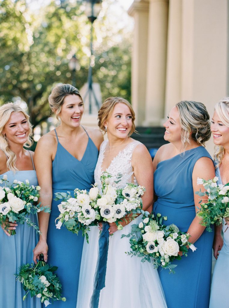 Bridesmaid in blue dresses holding bouquet with white florals