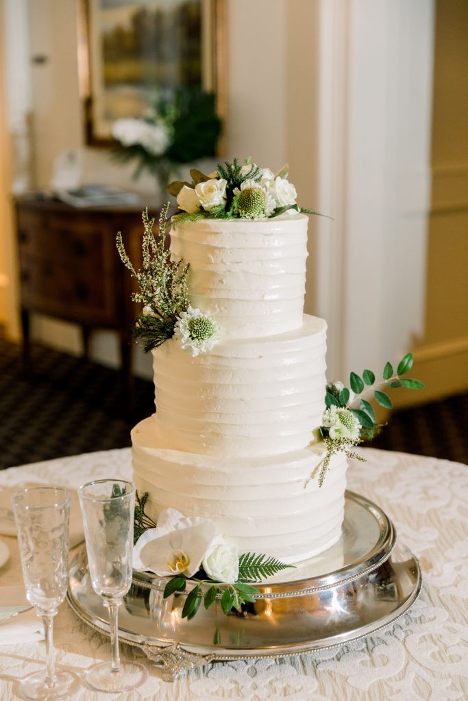 Buttercream wedding cake with white flowers and greenery
