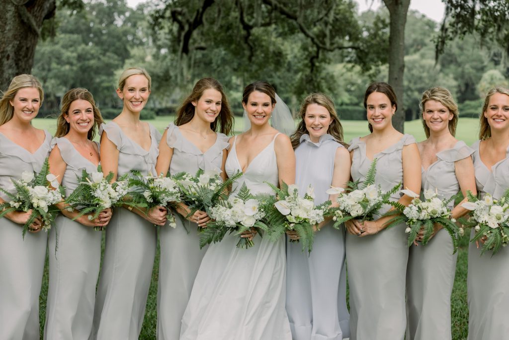 Bridesmaids holding white wedding bouquets and wearing grey bridesmaid dresses