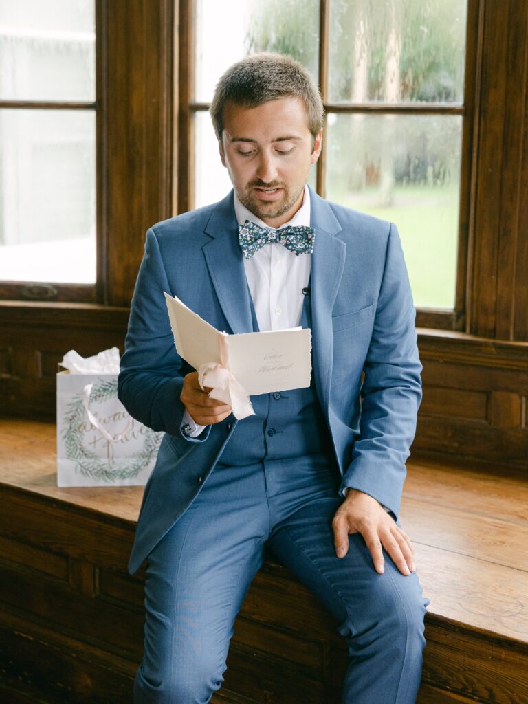 Groom in blue suit reading a card
