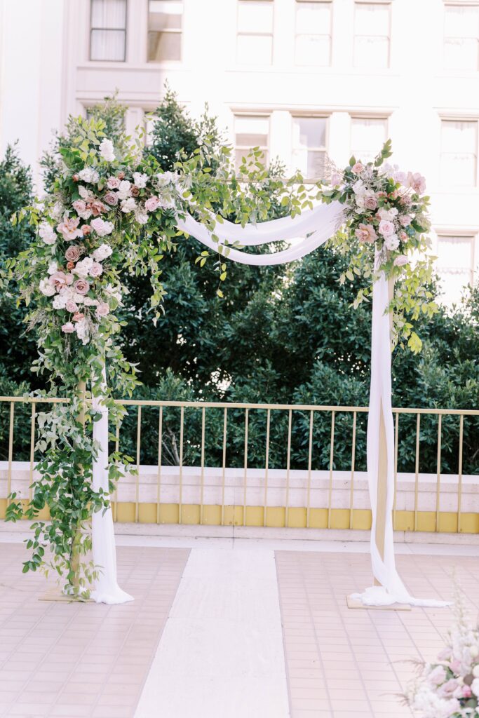 Wedding ceremony arch with draping and pink flowers