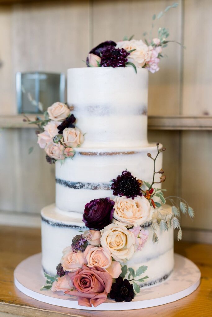 Three tiered naked wedding cake with fall flowers