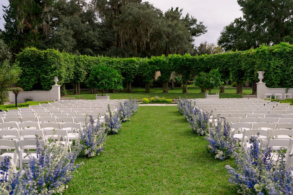 Wedding ceremony with blue and white flowers lining the aisle