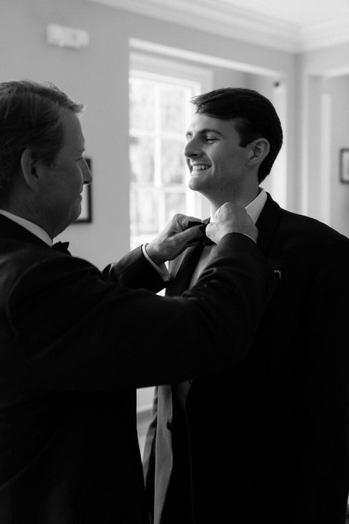 Black and white photo of dad tieing grooms bowtie