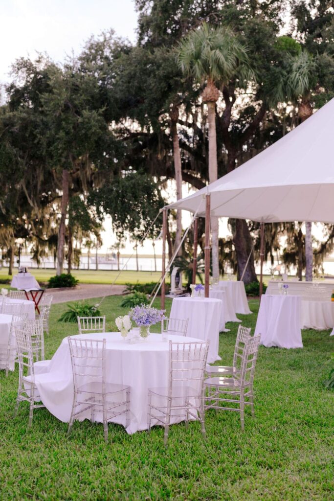 White tables and clear chairs at Jekyll Island Club tented wedding reception