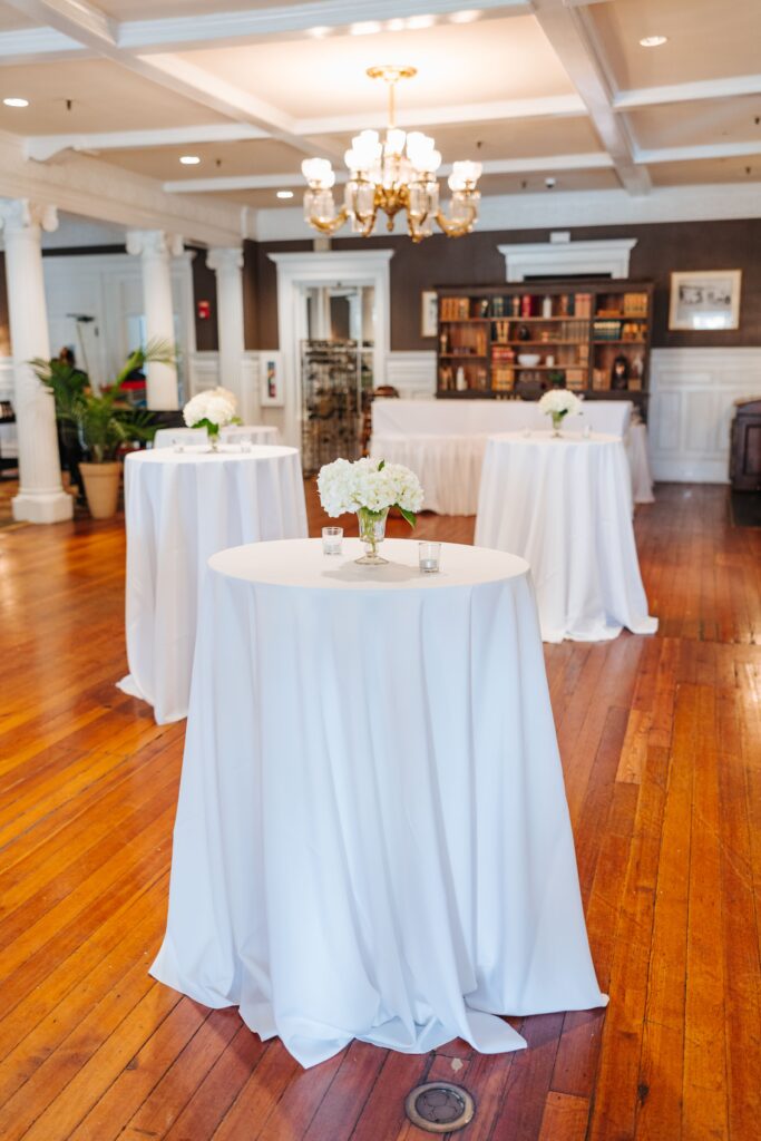 Cocktail tables with white linens and white flowers