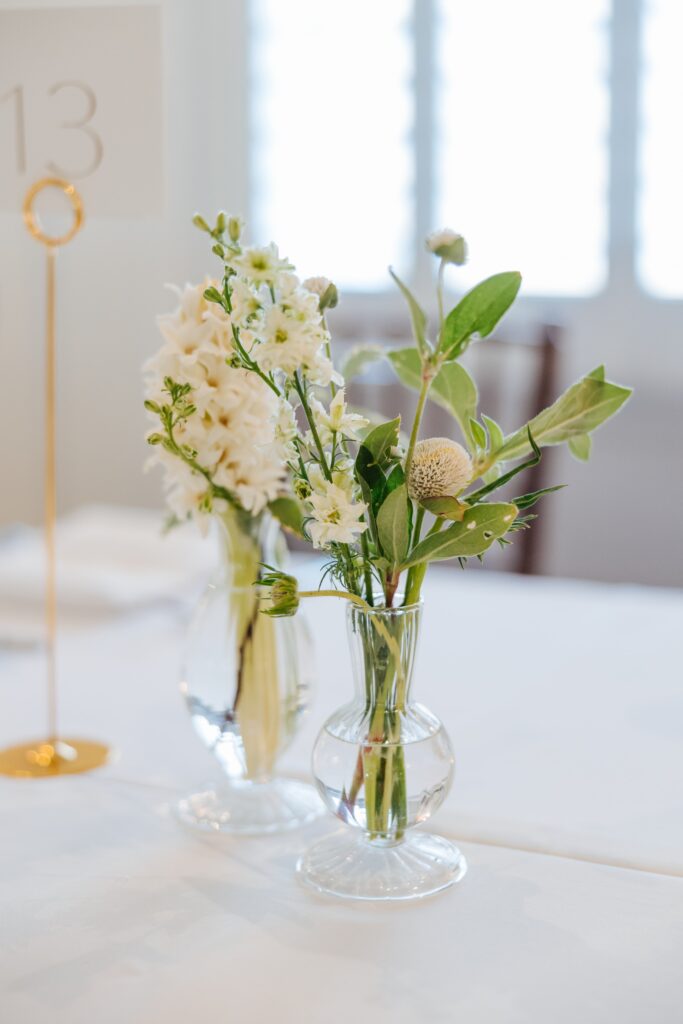 white flowers in bud vases on white table