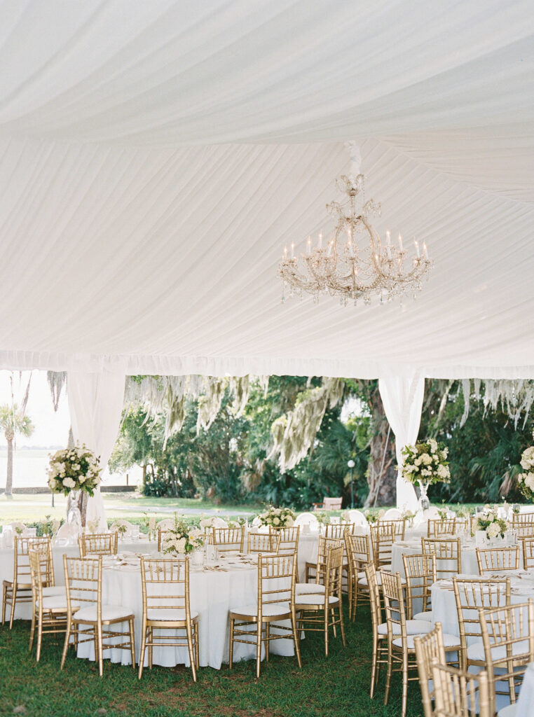 White tent with white tables and gold chairs