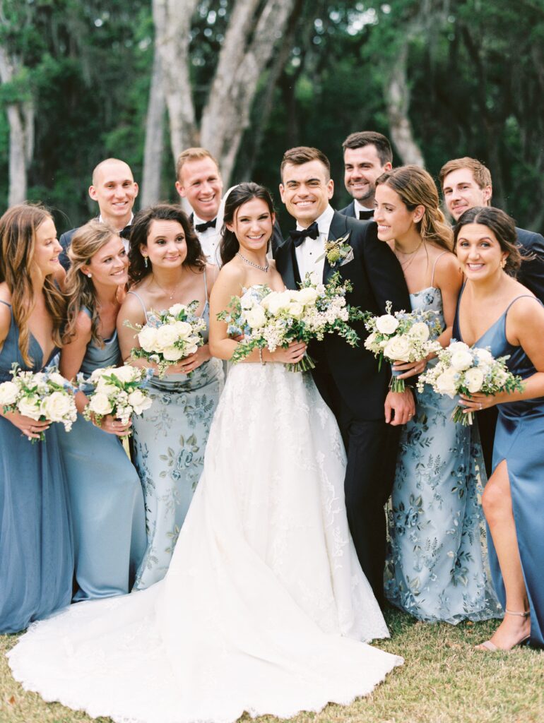 Wedding party in blue bridesmaid dresses and tuxedos with bride and groom