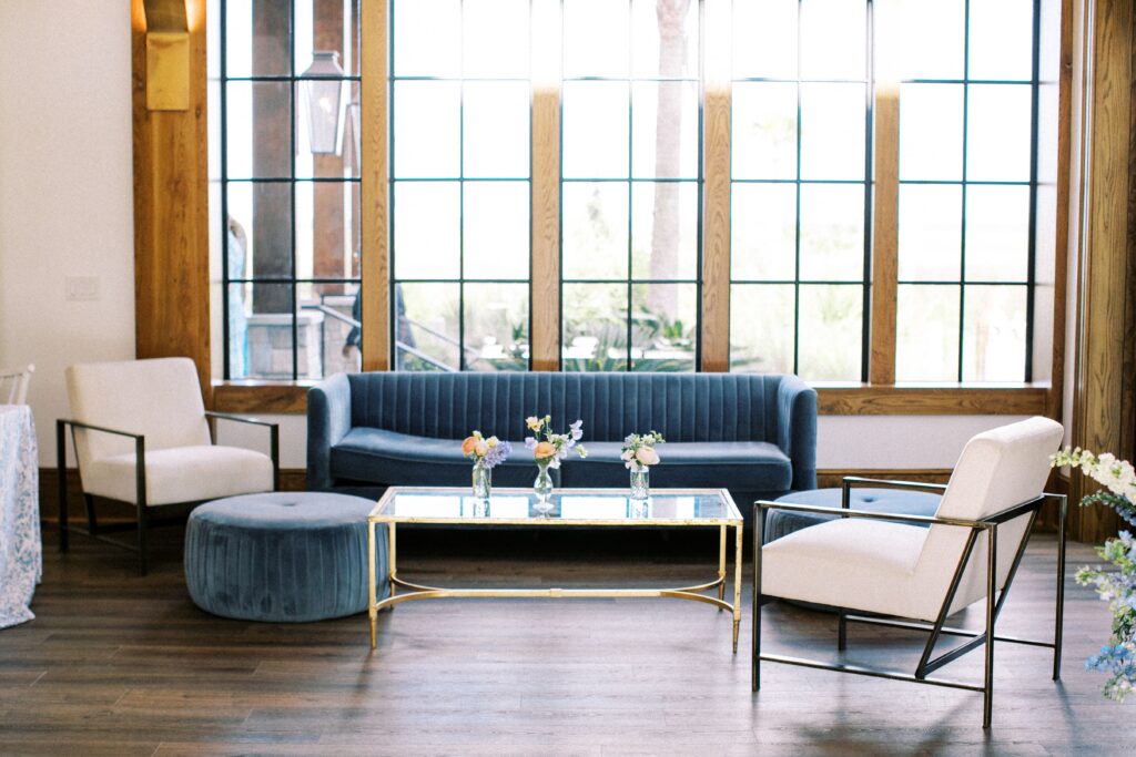 Blue velvet couch with white chairs and gold glass table
